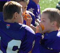 Youth football players enjoy oranges during half-time.