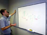 Two NetStarr employees try to make sense of the words and pictures left on an office white board.